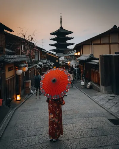 和のイメージの女性が傘をさして京の町を歩く画像