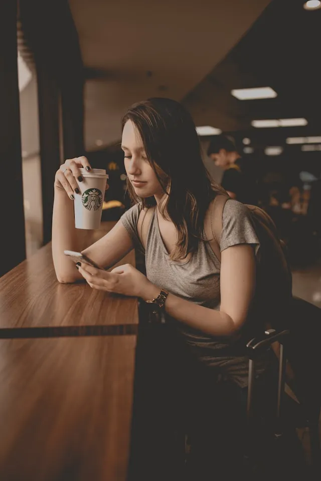 コーヒーとスマホを持っている女性